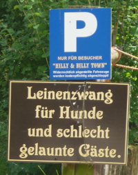 Oben Parkplatzschild für "Hillly & Billy Town" Besucher. Darunter ein Schild: "Leinenzwang für Hunde und schlecht gelaunte Gäste.